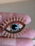 Broche dourado olho grego colorido na internet