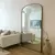 Espelho de chão Bali em uma sala de estar moderna com sofá bege e decoração minimalista.