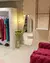 Espelho Orgânico Glow pendurado em uma parede com design de colmeia, refletindo parte de um ambiente de loja com roupas coloridas e decoração elegante.