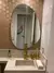 Espelho orgânico sem moldura instalado em banheiro moderno com decoração sofisticada e detalhes dourados na pia