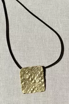 Collar artesanal con colgante cuadrado texturado en tono dorado y cadena negra tipo tanza.