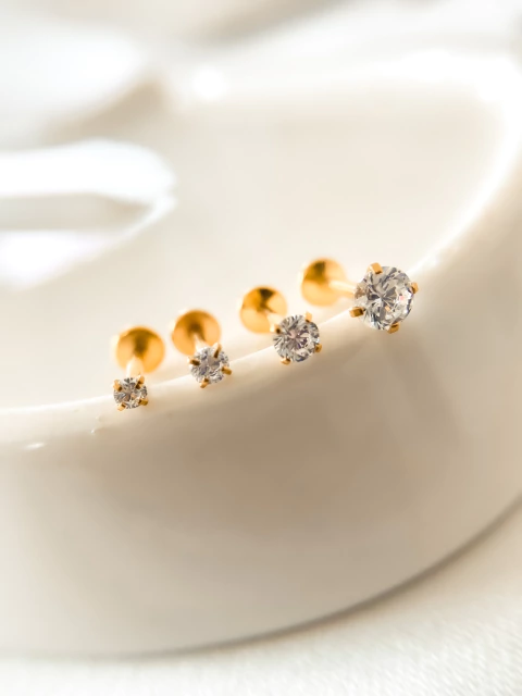 Piercings labret ponto de luz PVD gold em aço cirúrgico, com cristais brilhantes em diferentes tamanhos.