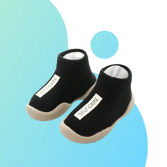 Um par de tênis meia infantis de cor preta com sola clara, da marca Self-Care®.