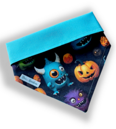 Bandana de tecido com estampa de monstros e abóbora, fundo escuro e detalhes coloridos.