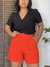 Bermudinha Bia em linho na cor laranja, com cintura alta e bolsos, combinada com blusa preta.