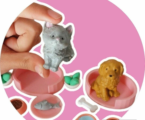 Miniaturas de un gato gris y un perro dorado junto a accesorios para mascotas.