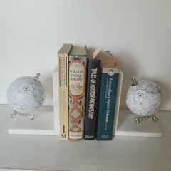 Estantería con libros clásicos y globos terráqueos decorativos a ambos lados, creando un ambiente acogedor.
