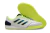 Chuteira de futsal Adidas com design moderno, predominantemente branca com detalhes em azul e verde neon, e solado emborrachado.