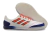 Chuteira Futsal Competition top IC da Adidas, com cabedal branco, detalhes em laranja e azul, ideal para jogos em quadra.