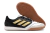 Chuteira de futsal Adidas com design preto e detalhes em dourado, sola em borracha não marcante.