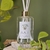 Difusor de ambiente White Tea / Chá Branco em frasco transparente com varetas, rodeado por folhas verdes. Inspiração Tânia Bulhões