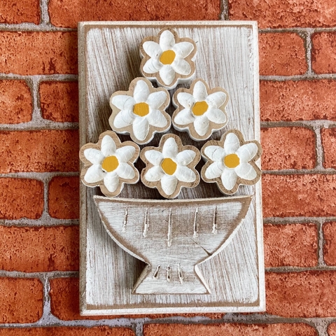 Quadro em alto relevo de um vaso com flores brancas e amarelas, em fundo rústico, ideal para decoração.