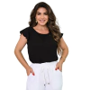 Mulher sorridente vestindo uma blusa preta com mangas bufantes e calças brancas, posando com as mãos nos bolsos.