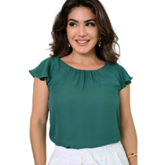 Mulher sorrindo, usando uma blusa verde com mangas curtas e onduladas.