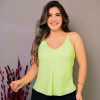 Mulher sorridente usando uma blusa verde-limão, com cabelo solto e brincos, em um fundo neutro.