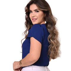 Mulher sorrindo de costas, com cabelo ondulado e blusa azul.
