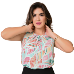 Mulher posando com blusa estampada colorida, cabelo solto e expressão confiante.