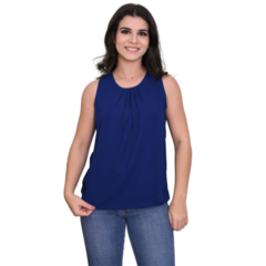 Mulher sorridente usando uma blusa azul escura e jeans, posando para a foto.
