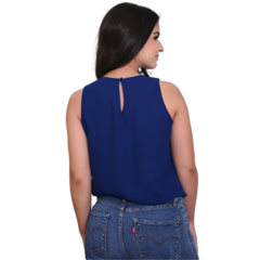 Mulher de costas usando blusa azul escura e jeans, com detalhe de botão na parte de trás da blusa.
