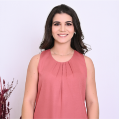 Uma mulher sorridente vestindo uma blusa rosa, com cabelo solto e brincos, em um fundo claro.