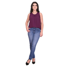 Modelo feminina posando com blusa roxa e jeans, usando sapatos pretos.