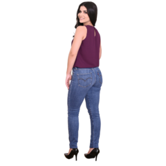 Modelo de vestido com blusa roxa e calça jeans, vista de costas, usando sapatos de salto alto.
