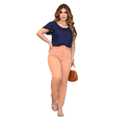 Mulher elegante usando blusa azul escura e calça rosa, posando com uma bolsa marrom.
