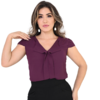 Modelo vestindo blusa roxa com detalhe em laço, posando com a mão no cabelo.