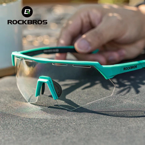 Óculos polarizado com quatro lentes, modelo da marca Rockbros, em primeiro plano sobre uma superfície escura.