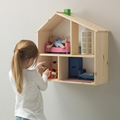 Uma criança brincando com uma casinha de bonecas de madeira, com móveis e bonecos, fixada na parede.