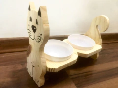 Comedouro duplo em formato de gato feito de madeira, com tigelas brancas para ração e água.