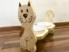 Comedouro duplo em formato de gato feito de madeira, com tigelas brancas para alimentos e água.
