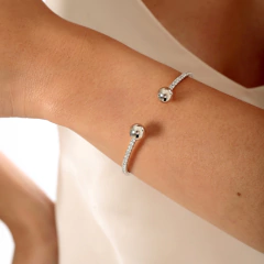 Bracelete aro ajustável, com pulseira cravejada em zircônias e uma esfera em cada ponta, banhado a Ouro 18k ou Ródio Branco.