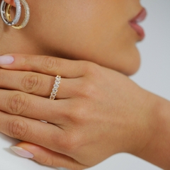 Anel banhado a Ouro 18k, tipo meia aliança com zircônias cravejadas em metade da circunferência. 