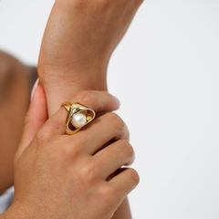 Anel em formato orgânico, banhado a Ouro 18k ou Ródio Branco, com pérola branca no centro. 