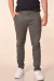 Homem vestindo calça masculina de sarja alfaiataria na cor grafite, com corte reto e bolso lateral, combinada com camiseta preta e tênis branco.