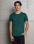 Camiseta Modal Slimfit verde, modelo masculino em pé, com fundo de parede de concreto.