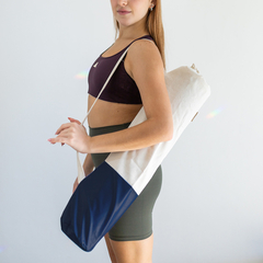 Mujer sosteniendo un bolso portamat de color azul y beige, ideal para yoga.