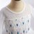 Detalhe do vestido infantil Elsa Frozen, com bordados em azul e branco.