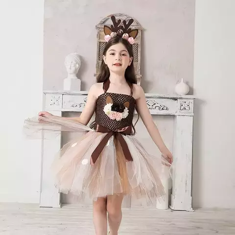 Menina vestindo uma fantasia de rena com acessórios, incluindo tiara com chifres e flores, em um ambiente claro.