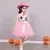 Menina vestindo fantasia de vaqueira infantil com estampa de vaca e saia rosa, usando um chapéu rosa.