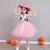 Menina vestindo fantasia de vaqueira infantil com saia de tule rosa e chapéu rosa, em frente a abóboras decorativas.