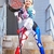 Cosplay de Arlequina, personagem famosa, usando um macacão colorido e segurando um bastão em uma escada.