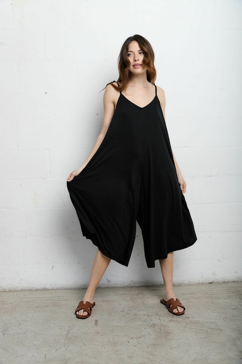 Mujer vistiendo un mono negro de tirantes, modelo Mono Over Basic, de la categoría Lo nuevo y Monoprendas/Vestidos