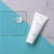 Creme hidratante facial da marca Extratos da Terra, com embalagem branca e detalhes em azul, ao lado de uma amostra do produto em uma superfície azul.
