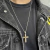 Pingente de cruz lisa em prata 925 usado como colar por pessoa com camiseta preta e jaqueta jeans preta