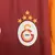 Camisa titular Galatasaray 2025/2026 masculina Puma, modelo oficial com design meio a meio em laranja e vinho, escudo do clube e estrela turca, para torcedores.