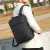 Homem usando uma mochila preta, com um fundo ao ar livre.