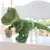 Boneco de pelúcia de um dinossauro T-Rex verde, com detalhes em listras e olhos expressivos.