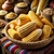 Um cesto de palha contendo espigas de milho amarelo, cercado por recipientes com grãos e especiarias ao fundo.